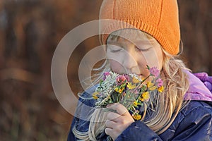 Girl closing her eyes sniffs the bouquet of wildflowers. Autumn.