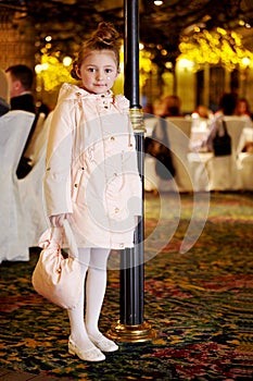 Girl in coat stands near to lamp post