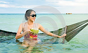 Girl with coconut on a tropical beach swing