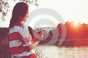 Girl with coffee at river sunrise