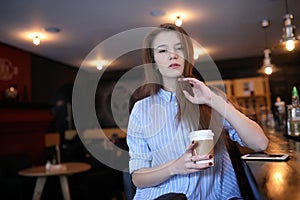 Girl with coffee. Young beautiful girl is sitting in a cafe and