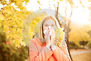 Girl with cold rhinitis on autumn background. Fall flu season. I