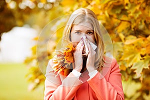 Girl with cold rhinitis on autumn background. Fall flu season. I