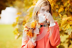 Girl with cold rhinitis on autumn background. Fall flu season. I