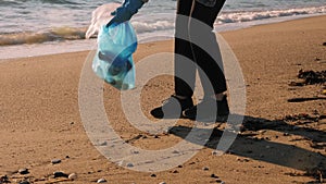 Girl collecting trash in trash bag on beach. Volunteer cleaning beach from garbage plastic waste bottles. Ecology environmental. P