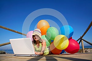 Girl with colorful alloons using a laptop