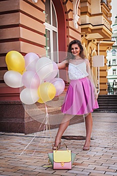 Girl with colorful latex balloons, urban scene, outdoors