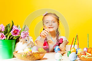 Girl colouring Eastern eggs and cute rabbit near