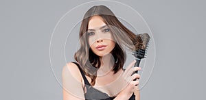 Girl combing hair. Beautiful young woman holding comb straightened hair.