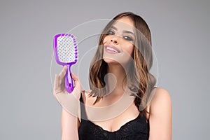 Girl combing hair with comb. Beautiful young woman holding hair comb. Female model hold comb near face. Woman portrait