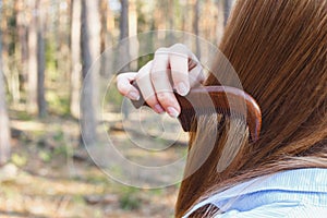 Girl combing hair with a wooden comb in the forest