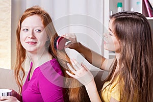 Girl combing hairs her friend