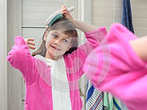 Girl combing her hair in the bathroom early in the morning