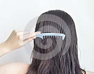 Girl combs long black hair comb, rear view, white background attractive