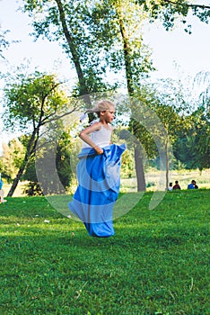 Girl compete in a relay race . jump in bag. They laugh and fall .