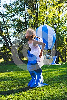 Girl compete in a relay race . Jumping in bags . They laugh and fall .