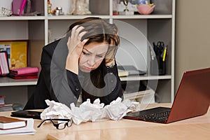 The girl at a computer with bunch crumpled sheets of paper