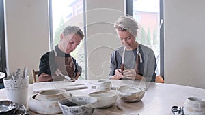 the girl conducts training for men with disabilities in clay modeling in a large and bright workshop. Rehabilitation of