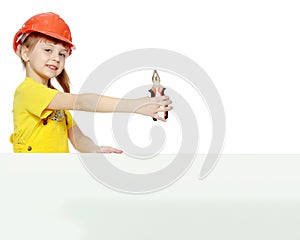 Girl in a construction helmet peeks out from behind a billboard.