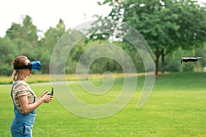 The girl controls a quadrocopter in the park with the help of a VR helmet. The concept of virtual reality. extra reality