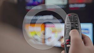 girl controls the TV remote control in room at home, rest on weekend, remote control of a modern smart TV, control TV