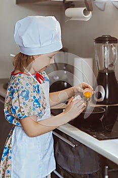 A girl cook cooks scrambled eggs. Stage three pours the egg into the frying pan. Soft focus