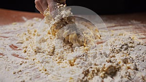 The girl cook kneads the dough from flour pours water from a glass into it
