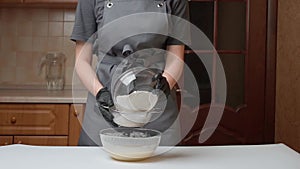 The girl cook pours flour in a sieve to sift before adding to the dough