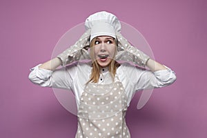 Girl cook in uniform, apron and gloves for baking screaming on a colored background, beautiful woman housewife in kitchen clothes