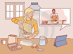 Girl cooks according to video recipe. Woman watches cooking blog, whipping eggs, online education, homemade food