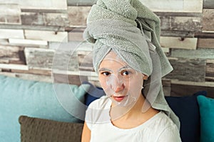 Girl in a cosmetic mask and a towel on her head. Makes home beauty treatments