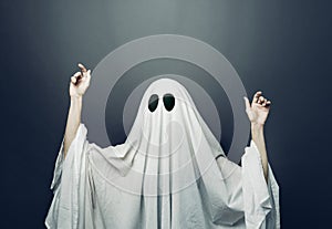 Girl in costume Spooky white ghost with black eyes on a gray background. Halloween minimal concept