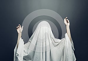 Girl in costume Spooky white ghost with black eyes on a gray background. Halloween minimal concept