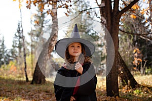 Girl in costume of witch in autumn forest.