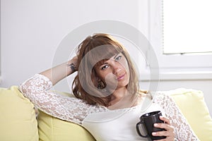 Girl on the couch relaxing holding a cup looking at you photo