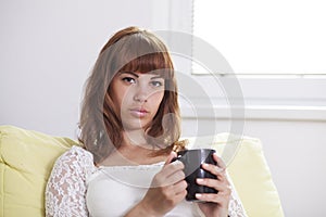 Girl holding a cup of tea looking at you photo