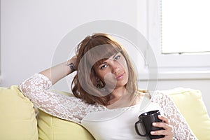 Girl on the couch relaxing holding a cup looking at you