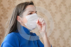 The girl coughs in a bandage. first signs of coronavirus. Girl in a white mask closes her mouth with her hand and coughs close-up