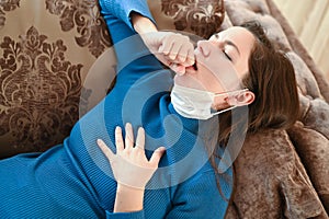 The girl coughs in a bandage. first signs of coronavirus. Girl in a white mask closes her mouth with her hand and coughs close-up