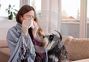 Girl covered with blanket blowing nose at home