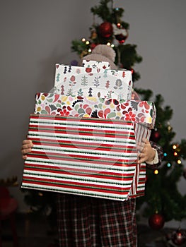 girl covered in gifts with christmas tree in the background. surprise. enthusiasm. consumerism