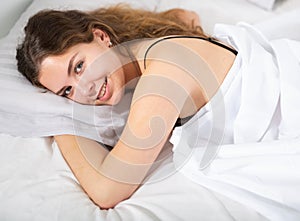 Girl covered with white bedsheet lying in bed