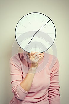 Girl covering her face from a clock. Woman hides from stress and deadline concept