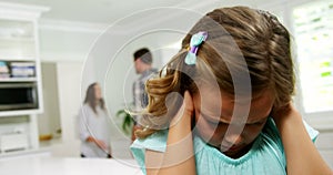 Girl covering his ears while parent quarreling in background