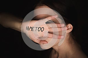 Girl covers her face with hand with hashtag metoo against harassment