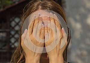 The girl covers her face with her hands
