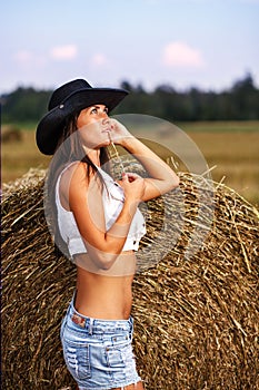 Girl in cowboy hat and jeans shorts with straw