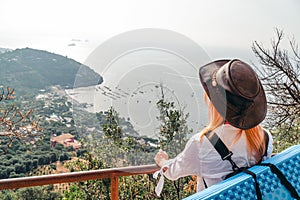 Girl in a cowboy hat made of kangaroo leather. Looks into the distance at sea and mountains. Bay with ships and the beach. Back