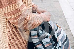Girl in a cozy beige sweater holds in hands a multi-colored backpack