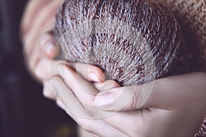 Girl in a cozy beige sweater holds in hands soft yarn coiled into a skein